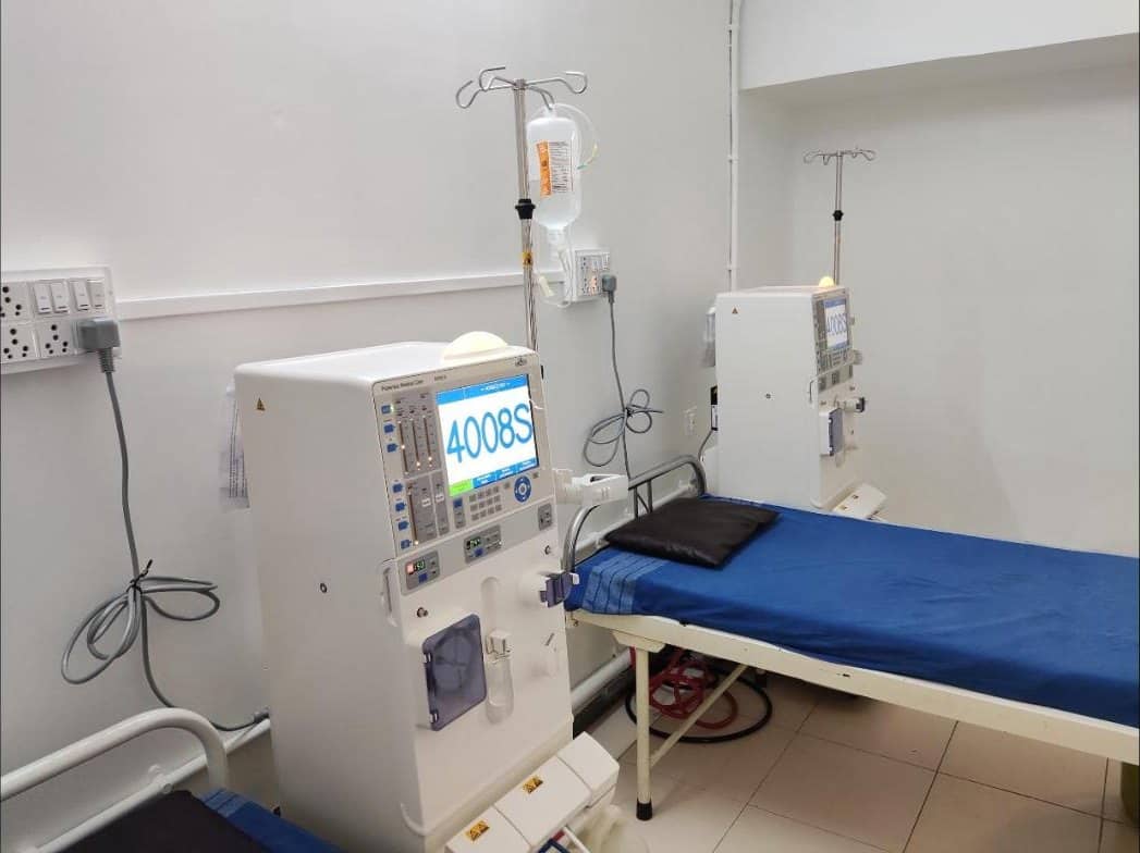 Dialysis machines beside patient beds in the dialysis unit